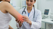 © Nedrofly - A healthcare professional assesses a woman's elbow pain in a clinical setting. The doctor is focused, using hands-on techniques to evaluate the issue while providing care