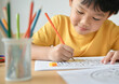 © Postmodern Studio - Asian male child solving maze puzzle with colored pencils at home