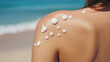 © Audtakorn - Sun Protection Application: A close-up shot showcases a person's shoulder, artfully adorned with dabs of sunscreen, ready to shield against the sun's rays on a beautiful beach day.