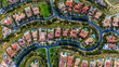 © Monet_P - High-resolution aerial photograph showing a planned neighborhood with curved streets and luxury homes with red tile roofs and backyard swimming pools in Newport Beach, California. The community is sur