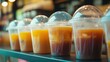 © DREAMERLYN STUDIO - Neatly aligned plastic cups with dome lids, ready for iced coffee or smoothies in a bright cafe environment