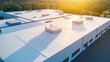 © Honey - Aerial view of commercial building with flat roof and vents at sunset with trees in background