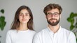 © Giman - A young couple standing side by side in a modern minimalist room, both wearing white shirts, neutral background with green plants, and indoor portrait.