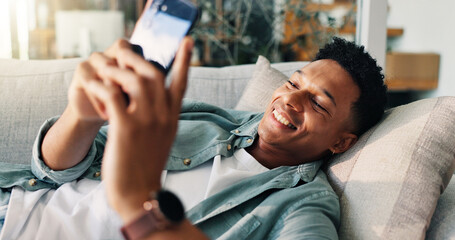 Fototapete - Man, happy and relax with phone on sofa for weekend break, dating site chat or streaming service. Smile, person or resting with smartphone in home with online subscription, social media or web scroll