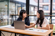 © Apichat - Two women are sitting at a table, talking to each other