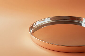 Poster - Shiny stainless steel serving tray on a warm orange background highlighting elegant design and modern aesthetics
