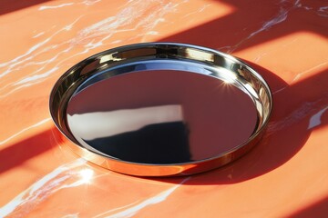 Poster - Reflective round tray placed on a marble surface illuminated by sunlight during the afternoon