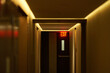 © Connect Images - Dimly lit hallway with illuminated exit sign and closed doors. New York City, NY, USA