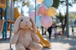 © Milos - A plush bunny sitting on a swing in a colorful playground, surrounded by vibrant balloons, depicts a joyful atmosphere in a children's play area on a sunny day.