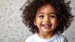 © creative - Portrait of smiling toddler girl with curly hair showing teeth