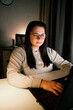 © Krievietka - Smiling millennial girl sitting at desk with computer scrolling internet, doing online shopping. Working on laptop in home office. Freelance work at home.
