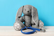 © New Africa - Pediatrics concept. Toy bunny with stethoscope on wooden table against light blue background