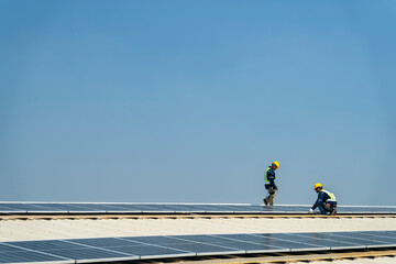 Wall Mural - two engineers install solar panels on a rooftop, wearing safety gear and helmets. the scene showcase