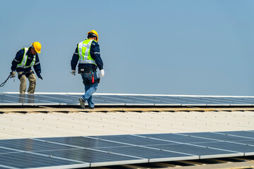 Wall Mural - two engineers install solar panels on a rooftop, wearing safety gear and helmets. the scene showcase