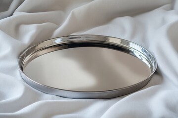 Leinwandbilder - Polished metal tray resting on soft fabric in a serene indoor setting during daytime light