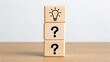 © Gibster - Stacked wooden blocks with a light bulb icon atop two blocks featuring question marks.