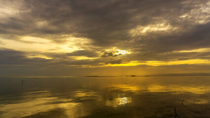 Wall Mural - sunset over calm waters with reflections and dramatic clouds