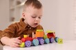 © New Africa - Motor skills development. Little boy playing with train toy at white table indoors
