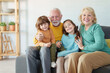 © Dorde - Caucasian Grandparents Sharing Joyful Moments With Their Smiling Grandchildren in a Bright and Cozy Home