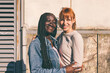 © Carlo Prearo - Two happy multi-ethnic friends embracing each other in the city
