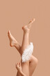 © Pixel-Shot - Legs of young woman with soft feather on brown background. Epilation concept