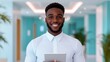 © CreativeSeven  - Confident African American manager in a modern office, smiling and holding a tablet, showcasing professionalism and positivity in the workplace.