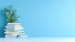 © yusufadi - Stack of Books with Greenery on a Light Blue Background