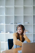 © Jirapong - Young woman enjoying a relaxing music break at her desk while using headphones, writing in a notebook, and working on her laptop for calm inspiration