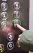 © Kufotos - Hand pressing ground floor button in modern elevator interior panel.