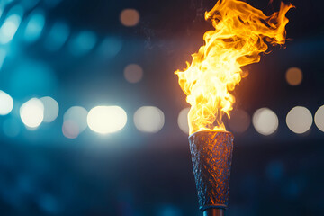 Wall Mural - Flame burns in Olympic torch against blurred sports arena