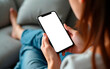 © Fobkk - Woman holding mobile phone resting on a sofa in the living room at home.