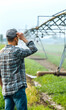 © Lucianastudio - Agricultural worker inspecting irrigation system in open farm during daytime