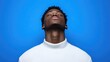 © Giman - Close-up portrait of a young man with eyes closed, head tilted back, against a vibrant blue background, wearing a white turtleneck