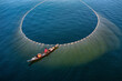 © AmazingAerialAgency - Aerial view of fishermen using a huge net on tranquil blue waters, Jibtali Union, Chattogram, Bangladesh.
