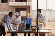 © Wosunan - Group of architects and engineers work together to assess the residential home construction site's progress
