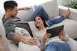 © New Africa - Couple with tablet resting on sofa in living room
