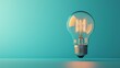 © Sarut - A single minimalist incandescent light bulb glowing against a vibrant blue background representing the spark of innovation creativity and the power of new ideas