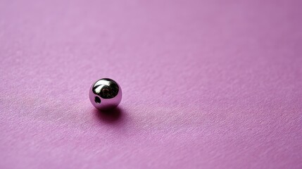 Poster - A silver bead rests on a smooth pastel backdrop, reflecting gentle light