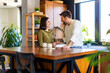 © we.bond.creations - Young loving couple standing at kitchen island, chatting, smiling and drinking coffee in modern apartment