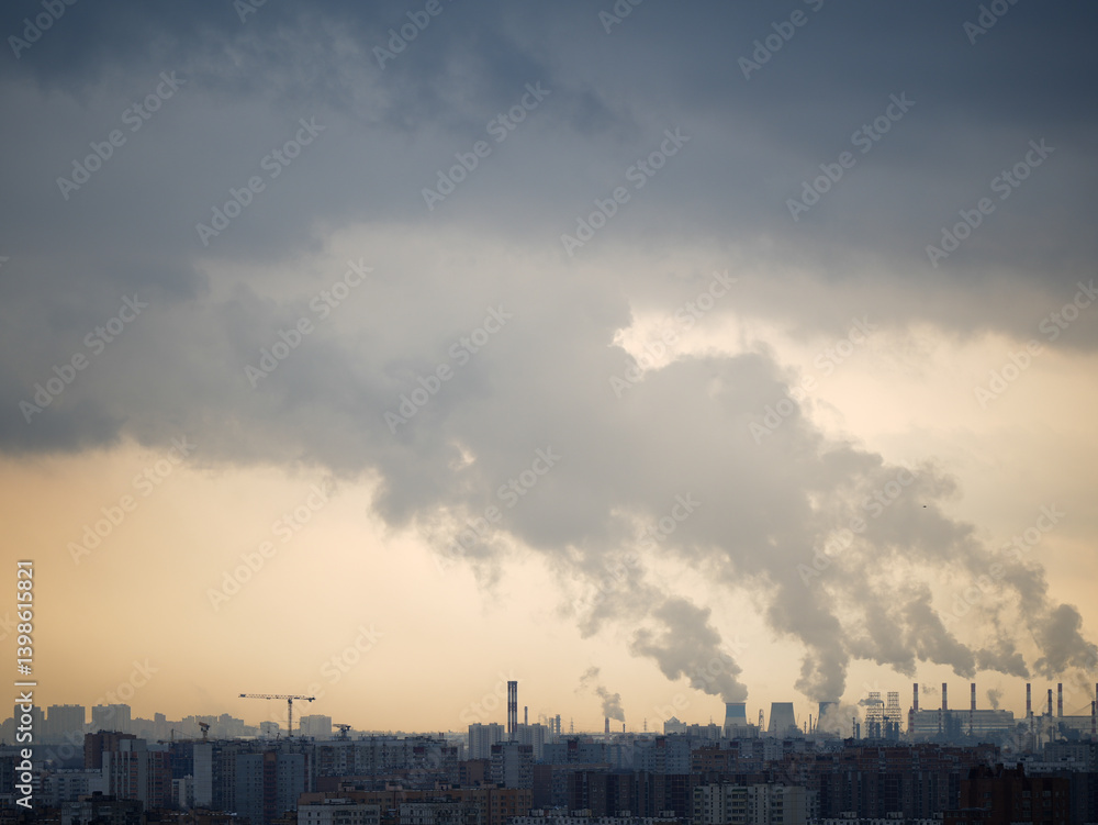 Panoramic view of a city with numerous residential buildings and an industrial area in the background. Factories emit thick smoke into the sky, causing severe air pollution