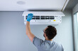 © Viktoriia - A Skilled Technician Performing Maintenance on a Ceiling-Mounted Air Conditioning Unit with Focus on Cleanliness and Efficiency in a Contemporary Indoor Setting
