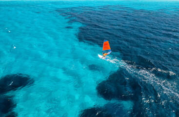 Wall Mural - aerial view of windsurfer on blue sea at sunny summer day. windsurfing. extreme sport and vacation. 