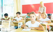© JackF - Focused girl sitting at desk writing test in classroom full of pupils during lesson