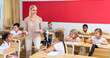 © JackF - Smiling woman teacher explaining new theme to children during class