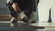 © aubriella - A Hispanic construction worker sealing joints in concrete at a construction site. Featuring attention to detail and care