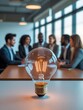 © Imagine  - Creative lightbulb symbolizing innovation in front of business team discussing ideas in modern office
