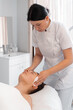 © Andrii - Cosmetologist wiping woman face with antibacterial napkins. Doctor performing beauty procedure in cosmetology clinic, cleaning the patient's face for treatment