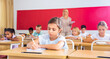 © JackF - Portrait of positive small female pupil sitting at desk studying in classroom