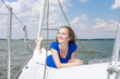 © danmorgan12 - Sea Travel Concepts. One Winsome Happy and Smiling Positive Caucasian Sailor Woman Laying On Deck Relaxing on White Yacht At Daytime on Board.