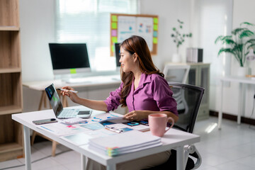 Fototapete - Asian businesswoman analyzing financial charts and graphs on laptop and digital tablet at office desk